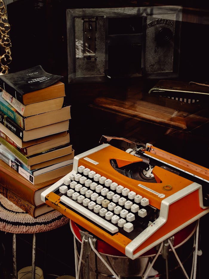 Retro orange typewriter beside a stack of books, capturing a nostalgic literary vibe.